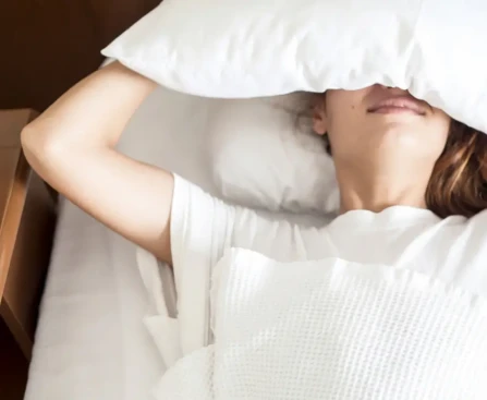 Traversin en lin naturel sur un lit style boutique-hôtel avec coussins neutres